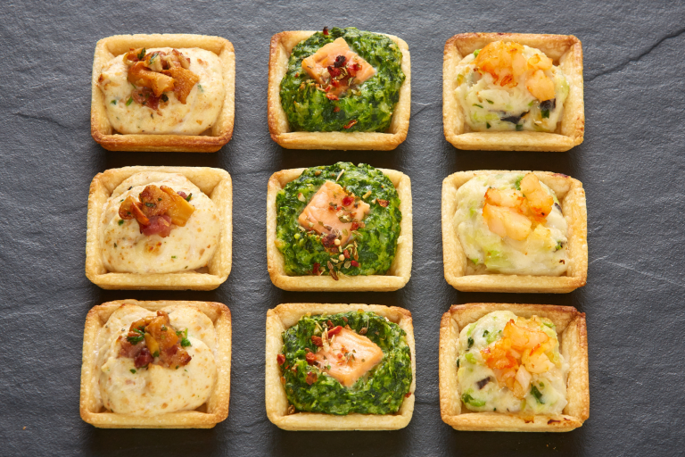 Gefüllte Quiche Verschiedene kleine Quiche mit herzhaften Füllungen auf einer Platte.